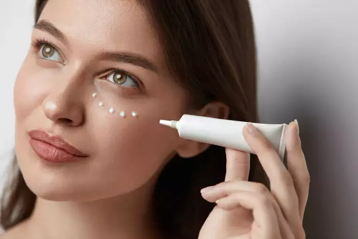 Applying eye cream suitable for oily skincare routine.
